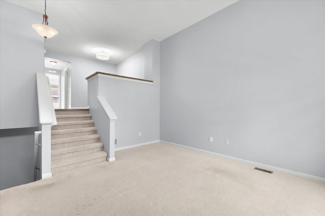 below grade area featuring visible vents, carpet flooring, baseboards, and stairway