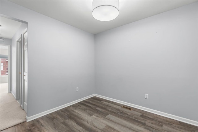 empty room with baseboards, wood finished floors, and visible vents