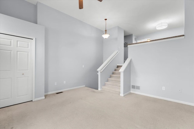 unfurnished living room featuring carpet flooring, ceiling fan, visible vents, and baseboards