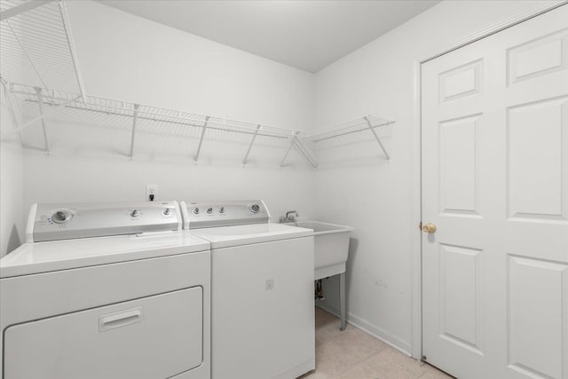 clothes washing area with laundry area, a sink, washing machine and dryer, and baseboards
