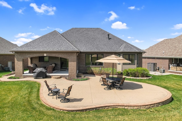 rear view of house with brick siding, a patio area, and roof with shingles