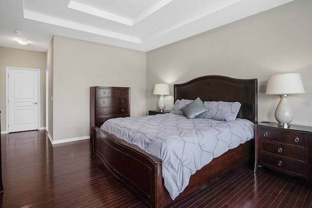 bedroom featuring baseboards, a raised ceiling, and wood finished floors