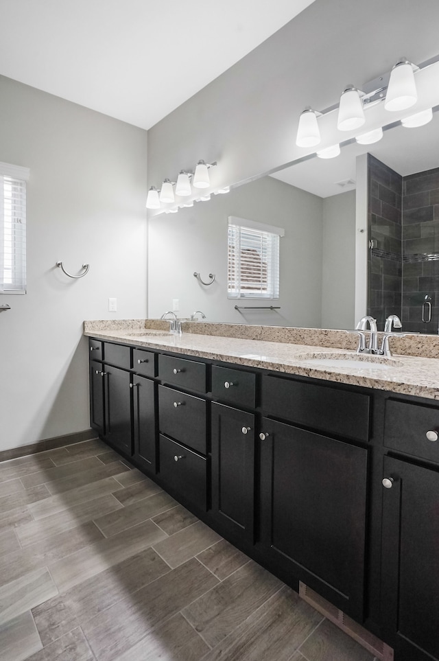 bathroom with double vanity, a sink, a stall shower, and a wealth of natural light