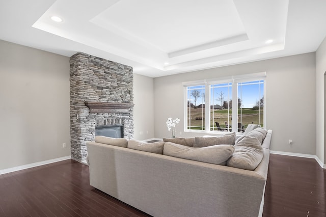 living room with recessed lighting, a raised ceiling, a fireplace, and dark wood-style floors