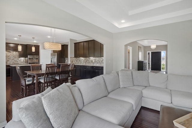 living area featuring dark wood-type flooring, arched walkways, and recessed lighting