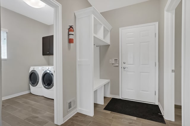 clothes washing area with visible vents, cabinet space, independent washer and dryer, and baseboards