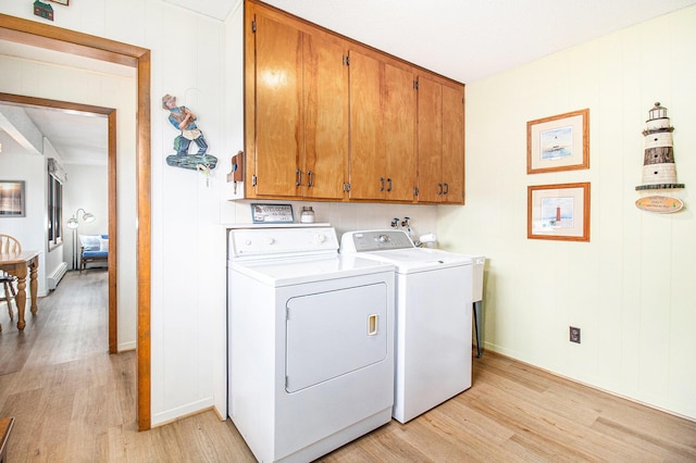 laundry room featuring cabinet space, baseboards, a baseboard radiator, light wood-style floors, and washer and clothes dryer