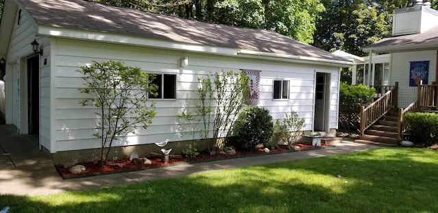 view of side of home featuring a shingled roof and a yard