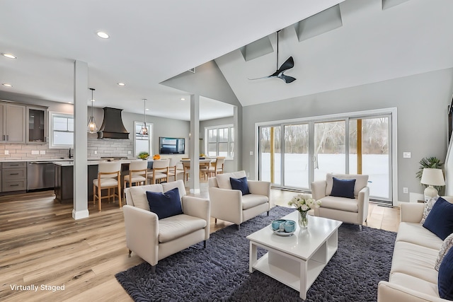 living room with recessed lighting, lofted ceiling, a wealth of natural light, and light wood-style flooring