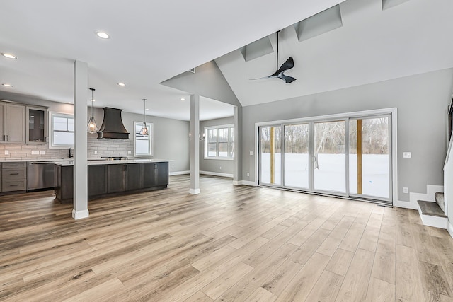 unfurnished living room featuring ceiling fan, a sink, recessed lighting, baseboards, and light wood-type flooring