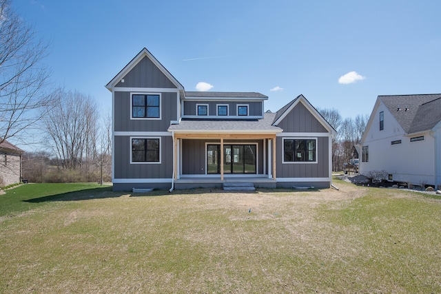 rear view of property featuring a lawn, covered porch, and a shingled roof