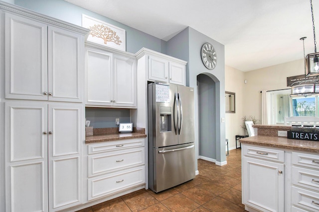 kitchen with arched walkways, pendant lighting, white cabinetry, and stainless steel fridge with ice dispenser
