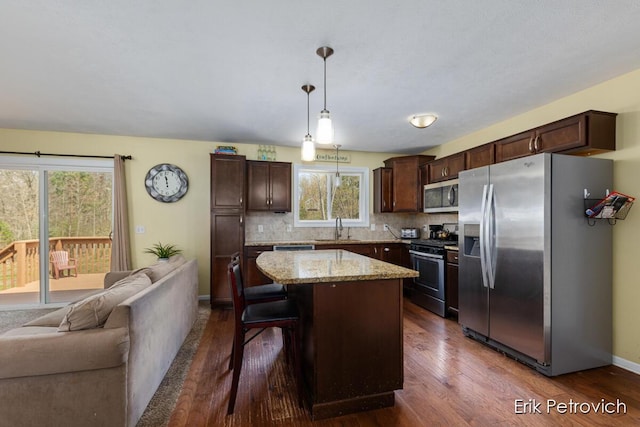 581 Cumings Ct NW, Sparta, MI 49345 - kitchen featuring dark brown cabinetry, appliances with stainless steel finishes, open floor plan, and dark wood-type flooring