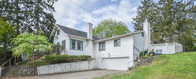 exterior space with a garage, a chimney, driveway, and stucco siding