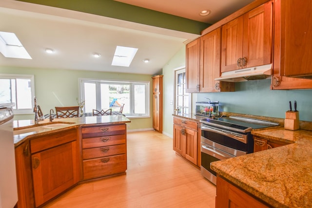 kitchen featuring brown cabinetry, under cabinet range hood, double oven range, and light stone countertops
