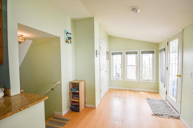 foyer with baseboards, vaulted ceiling, and wood finished floors