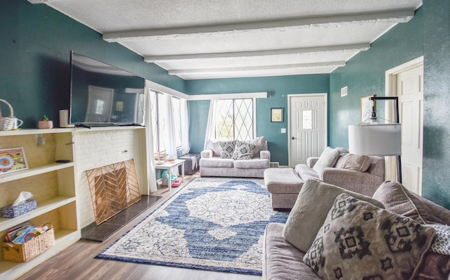 living room with a textured ceiling, wood finished floors, and beamed ceiling