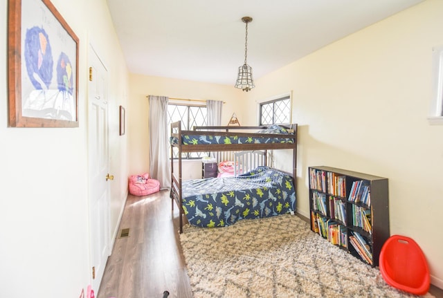 bedroom with baseboards, wood finished floors, and visible vents
