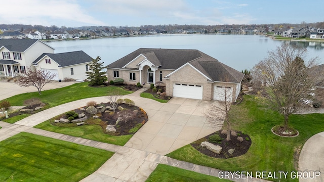 view of front of home featuring a residential view, a garage, a front lawn, concrete driveway, and a water view