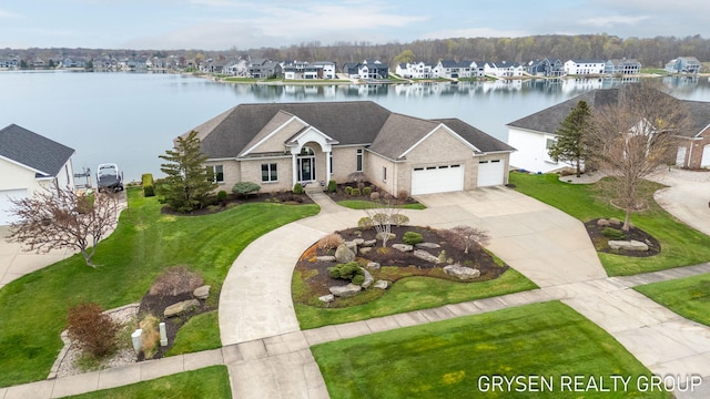 view of front of property with roof with shingles, a front lawn, a garage, a water view, and concrete driveway