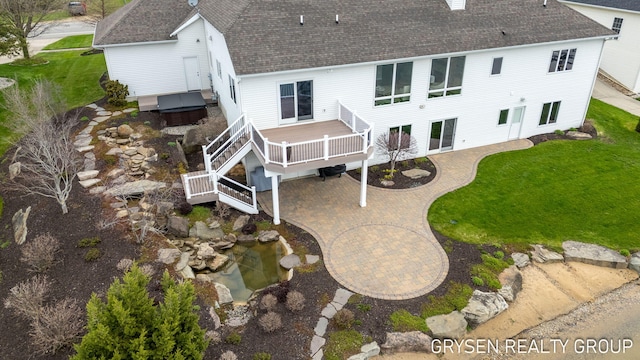 rear view of property featuring a lawn, a shingled roof, and a patio area