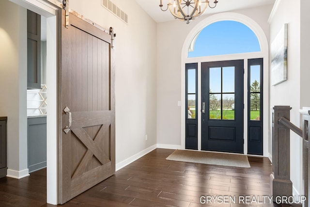 foyer with visible vents, a barn door, and dark wood finished floors