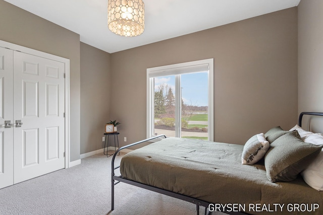 carpeted bedroom with baseboards and a chandelier