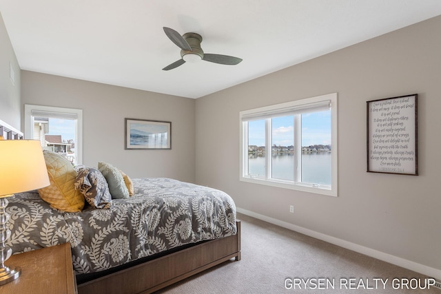 bedroom featuring baseboards, ceiling fan, carpet flooring, and a water view