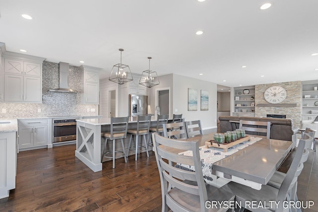 dining area featuring recessed lighting, a fireplace, dark wood-style floors, and built in shelves