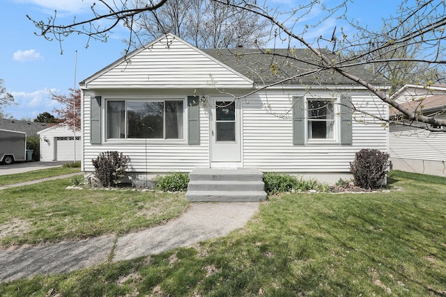 view of front of home featuring a detached garage, a shingled roof, an outdoor structure, and a front yard