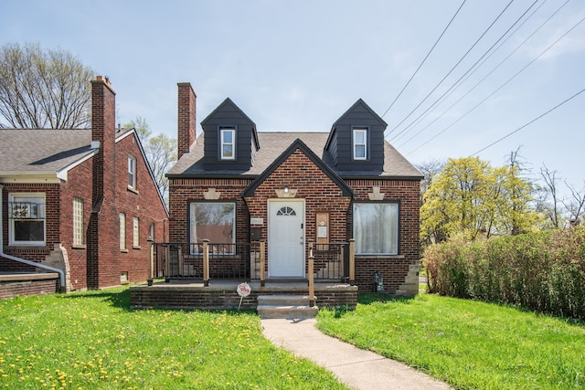 view of front of house with a shingled roof, a front lawn, and brick siding