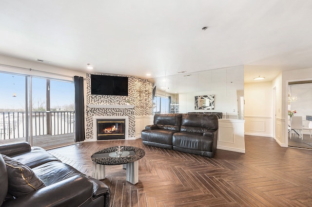 living area with wainscoting, a fireplace, a decorative wall, recessed lighting, and visible vents