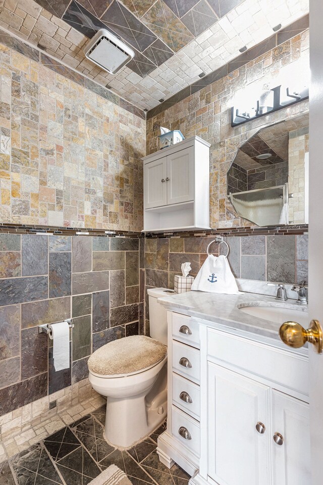 bathroom with vanity, toilet, and tile walls