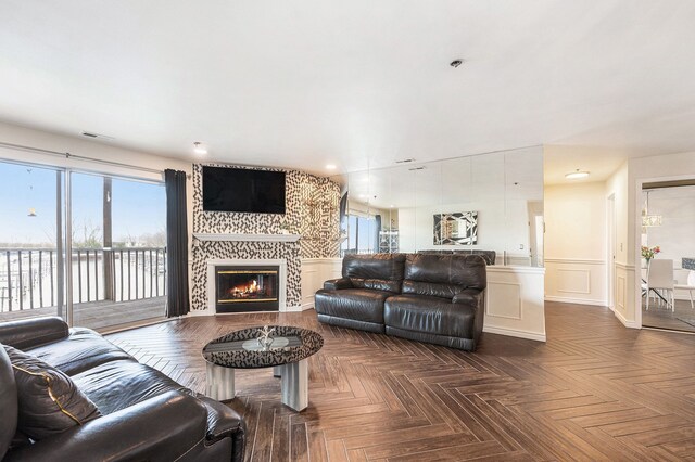 living area with wainscoting, a fireplace, a decorative wall, recessed lighting, and visible vents