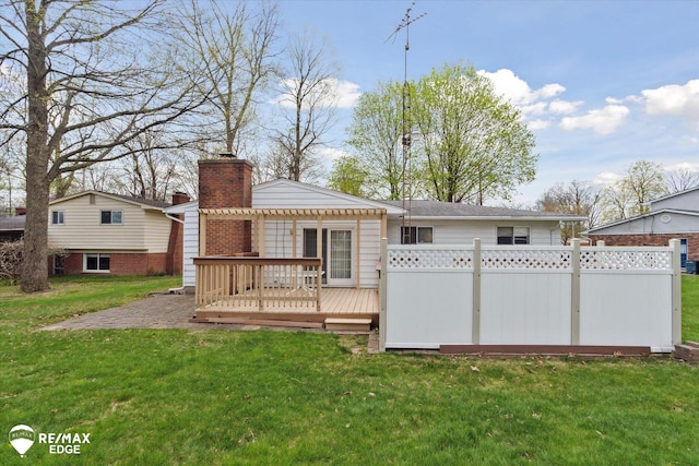 rear view of property with a lawn, a deck, fence, and a chimney