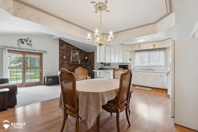 dining space featuring a notable chandelier, light wood-style flooring, and lofted ceiling