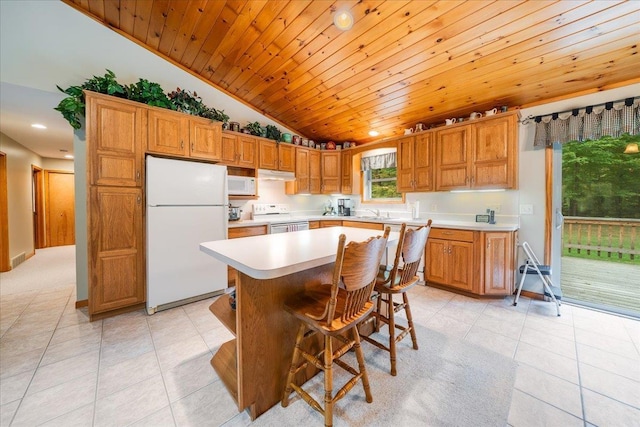 4335 Kings Corner Rd, Glennie, MI 48737 - kitchen with vaulted ceiling, light tile patterned floors, light countertops, under cabinet range hood, and white appliances