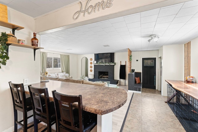 8119 N Dort Hwy, Mount Morris, MI 48458 - kitchen featuring a breakfast bar area, open shelves, a fireplace, a peninsula, and light tile patterned flooring