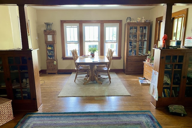 dining area featuring baseboards, ornate columns, and wood finished floors