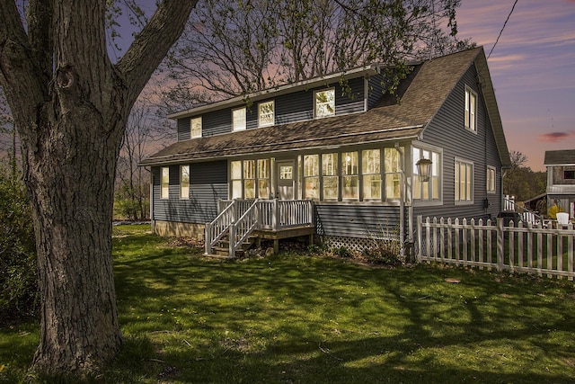 view of front of house featuring a shingled roof, fence, and a yard