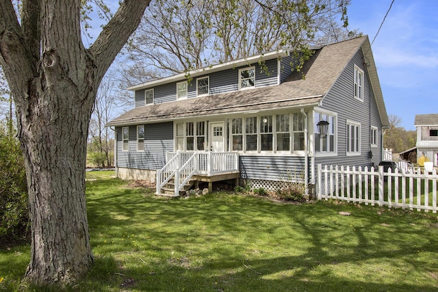 view of front of house featuring a shingled roof, fence, and a front yard