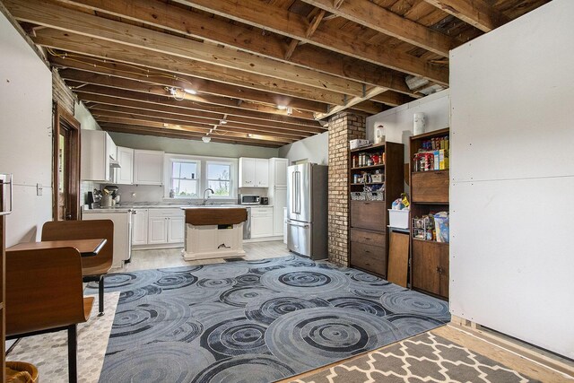 interior space with a center island, light countertops, white cabinetry, a sink, and stainless steel appliances