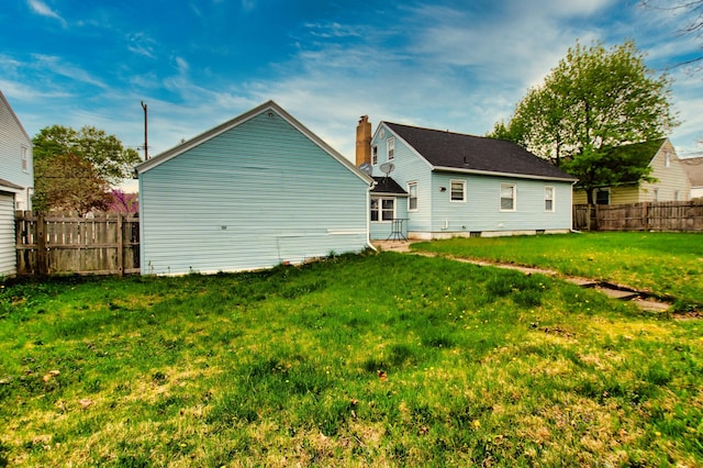 back of property featuring a lawn and fence