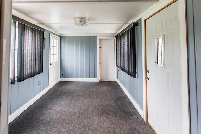 unfurnished room with baseboards and dark carpet