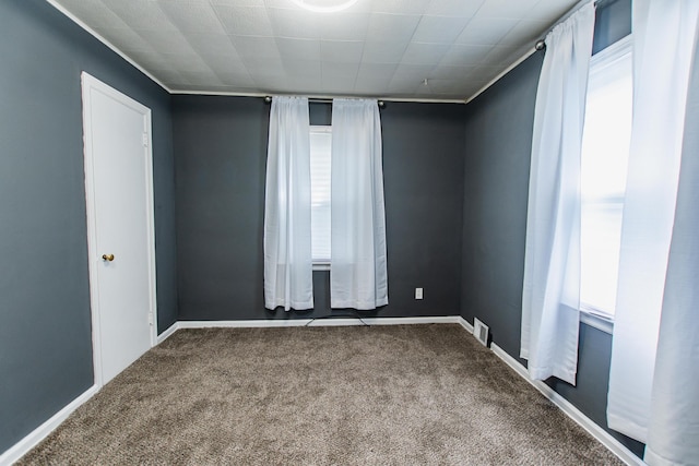 empty room with baseboards, visible vents, and carpet