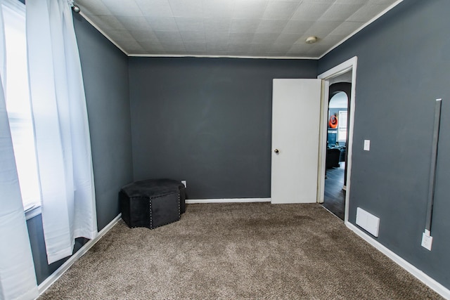 empty room with carpet floors and arched walkways