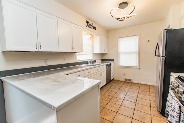kitchen with visible vents, appliances with stainless steel finishes, a sink, light tile patterned floors, and white cabinets