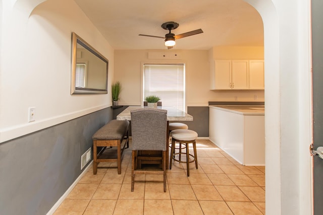 dining space featuring a ceiling fan, visible vents, arched walkways, baseboards, and light tile patterned flooring