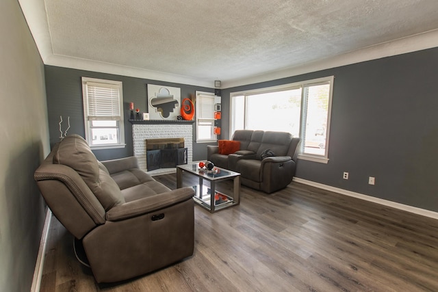 living area featuring baseboards, a textured ceiling, a brick fireplace, and wood finished floors