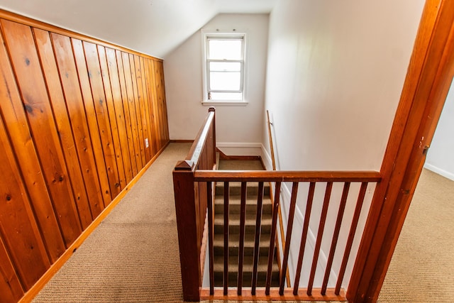 staircase featuring baseboards, lofted ceiling, and carpet